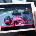 Copenhagen, Denmark - April 22, 2016: Two hands hold an Apple iPad while it is streaming video from a Formula One race. The image on the screen shows the race from the point of view of Ferrari driver Kimi Raikkonen who enters a turn on the F1 track in his red race car.