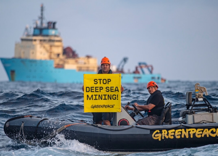 Victor, a Greenpeace International activist from Fiji displays a banner in front of the Maersk Launcher, a ship chartered by DeepGreen, during a protest against deep sea mining in the Pacific, April 5, 2021. Marten Van Dijl/Greenpeace/Handout via REUTERS